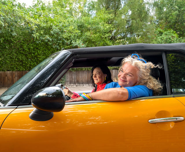Two people smiling inside orange car
