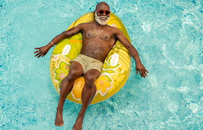 A person lounging on a bright floral inflatable in a clear blue swimming pool.